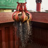 Red grapple lifting a scoop of waste for incineration.