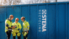 Tre personer i varselkläder som står vid en container
