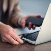 A Stena Recycling customer works on a laptop while holding a mobile phone