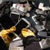 A Stena Recycling expert wearing protective gloves sorts a container of used mobile phones 