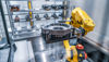 Yellow industry robot arm lifting a cast metal workpiece